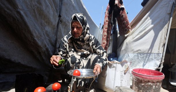 Displaced Palestinian woman Nisreen Abu Saada cooks vegetables over a wood fire outside her tent, amid shortages of lighters and cooking gas, Khan Younis, Gaza Strip, Palestine, July 21, 2026. (Reuters Photo)