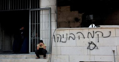 A Palestinian boy sits near a mosque torched by illegal Israeli settlers in Qusra near Nablus, in the Israeli-occupied West Bank, July 26, 2026. (Reuters Photo)