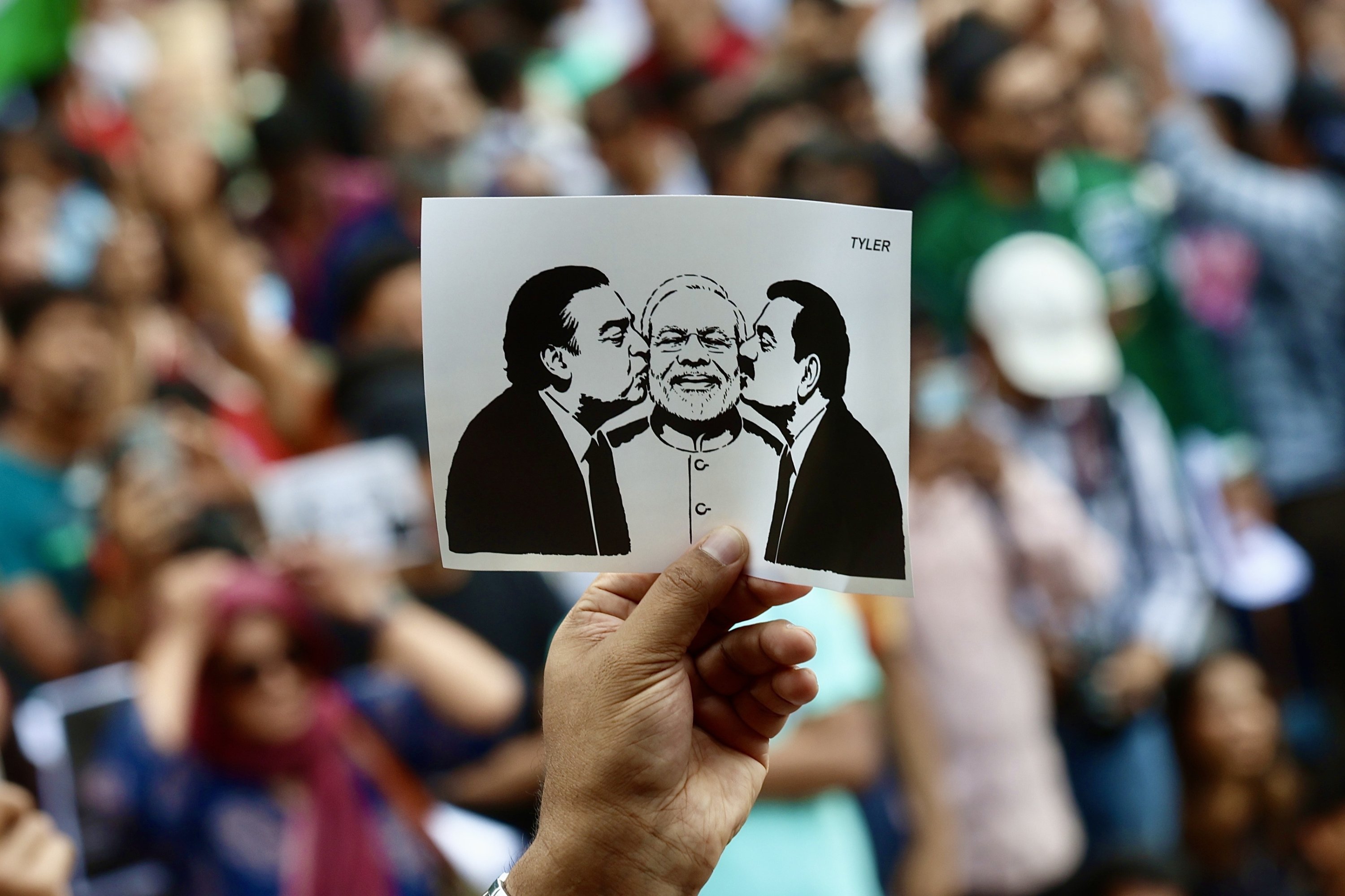A protester holds a placard showing Indian Prime Minister Narendra Modi (C) as he is kissed by Indian businessman Mukesh Dhirubhai Ambani (L) and Indian billionaire businessman, Chairman of Adani Group Gautam Adani (R) during a protest in Bangalore, India, July 25, 2026. (EPA Photo)
