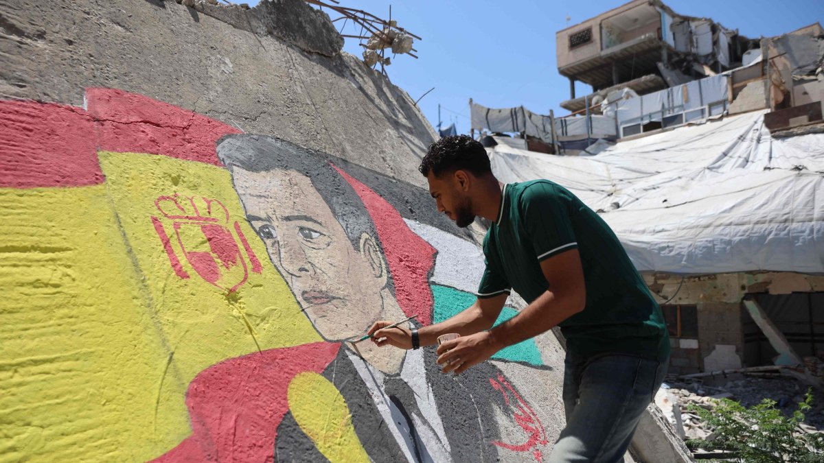 Gazan artist Ubay Karim al-Qurshali, retouches the mural he painted on the rubble of homes destroyed by the Israeli army in Gaza City, July 27, 2026. (AFP Photo)