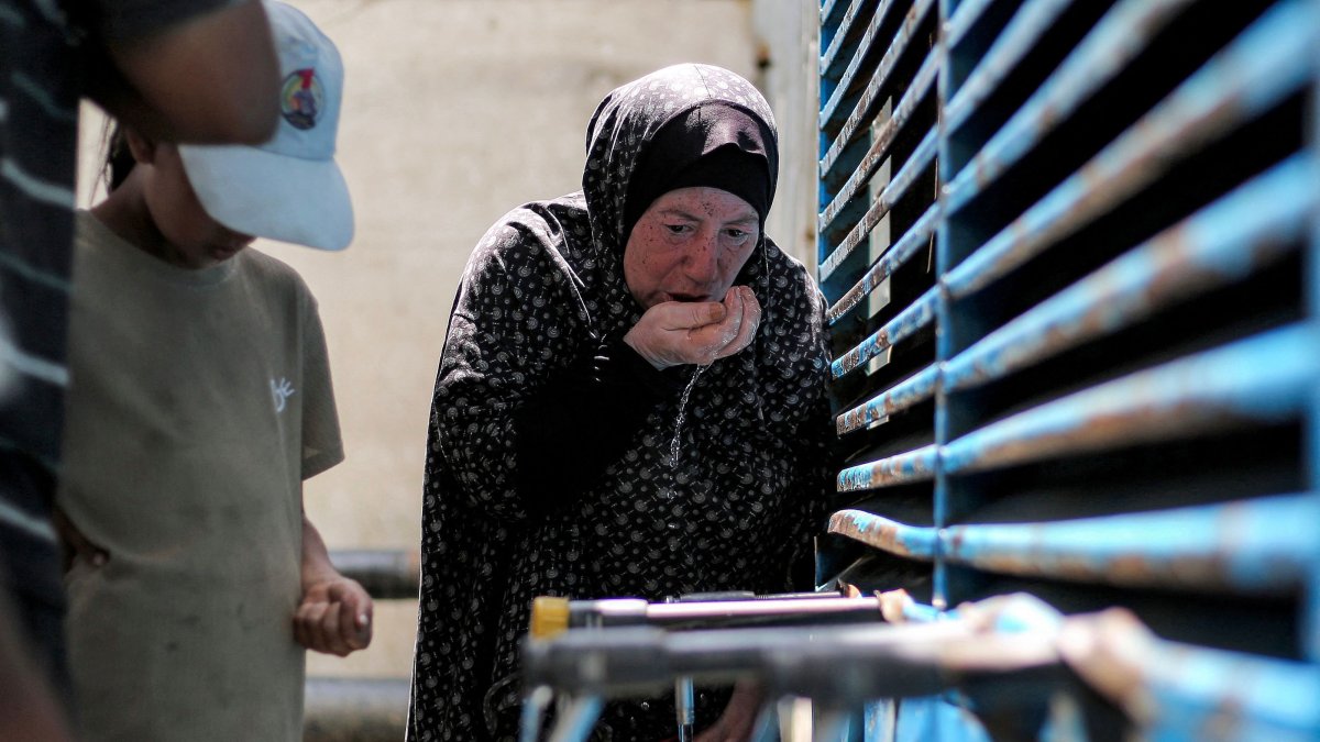 A woman uses her hands to have a drink of water as people queue to fill up their containers from a cistern at the Maghazi camp for Palestinian refugees in the central Gaza Strip, July 26, 2026. (AFP Photo)
