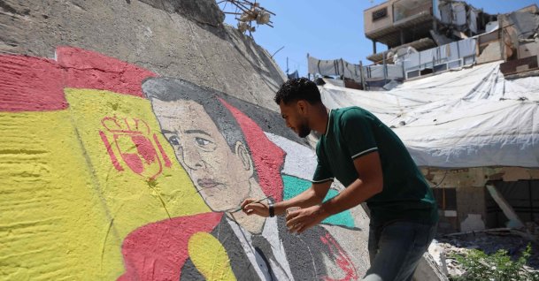 Gazan artist Ubay Karim al-Qurshali, retouches the mural he painted on the rubble of homes destroyed by the Israeli army in Gaza City, July 27, 2026. (AFP Photo)