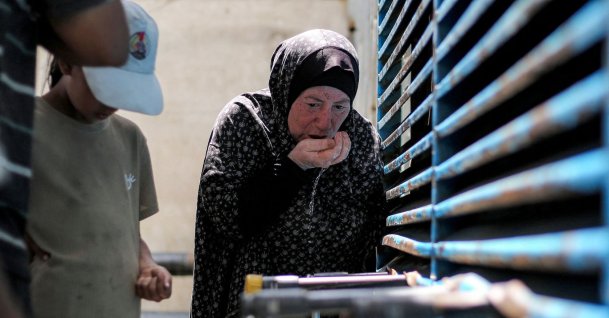 A woman uses her hands to have a drink of water as people queue to fill up their containers from a cistern at the Maghazi camp for Palestinian refugees in the central Gaza Strip, July 26, 2026. (AFP Photo)