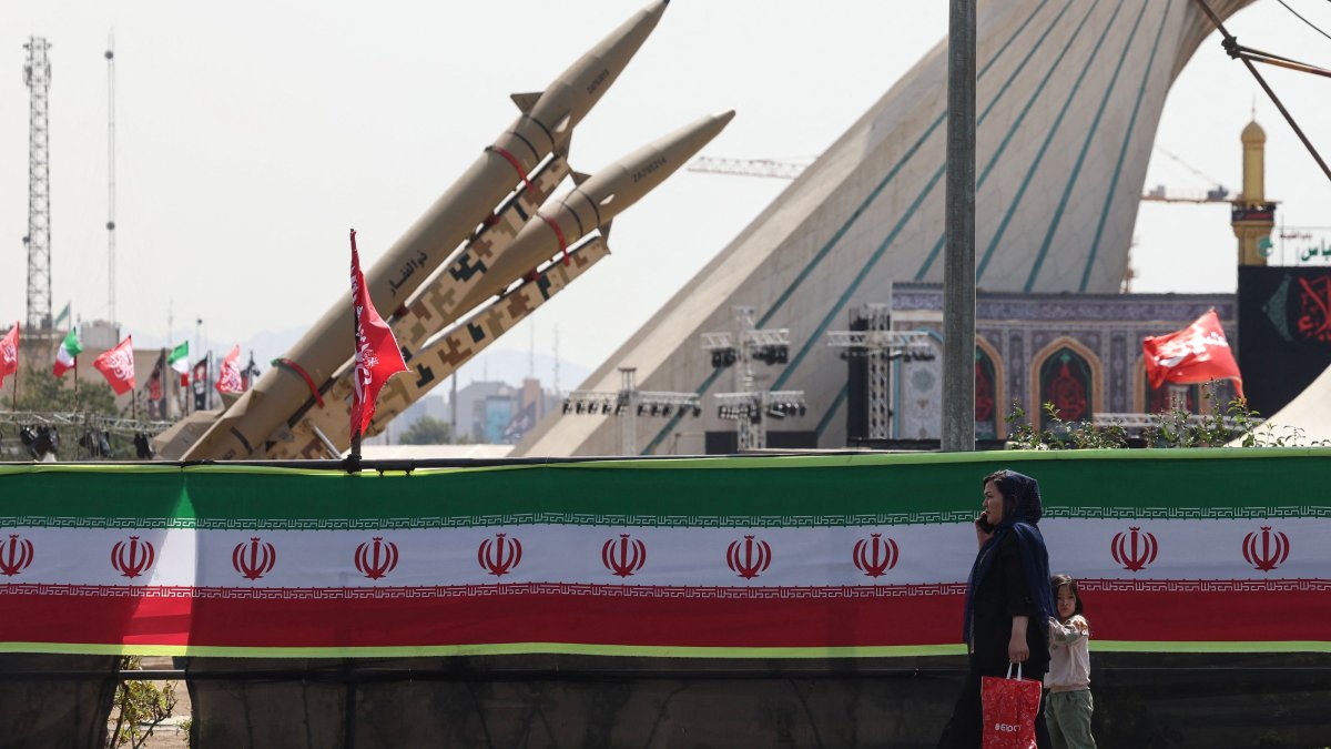 A woman and a child walk past Iranian-made Zolfaghar missiles displayed at Azadi Square in Tehran, Iran, July 24, 2026. (AFP Photo)