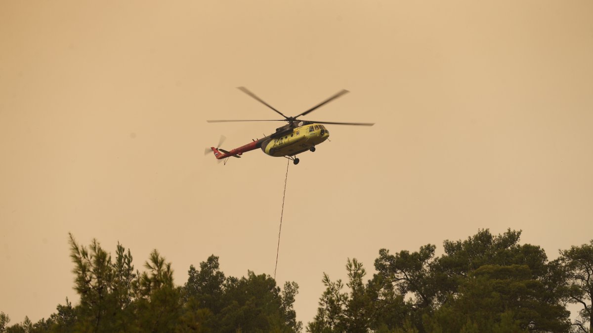 A helicopter drops water over a wildfire as firefighters battle the blaze, Seydikemer, Muğla, Türkiye, July 29, 2026. (AA Photo)