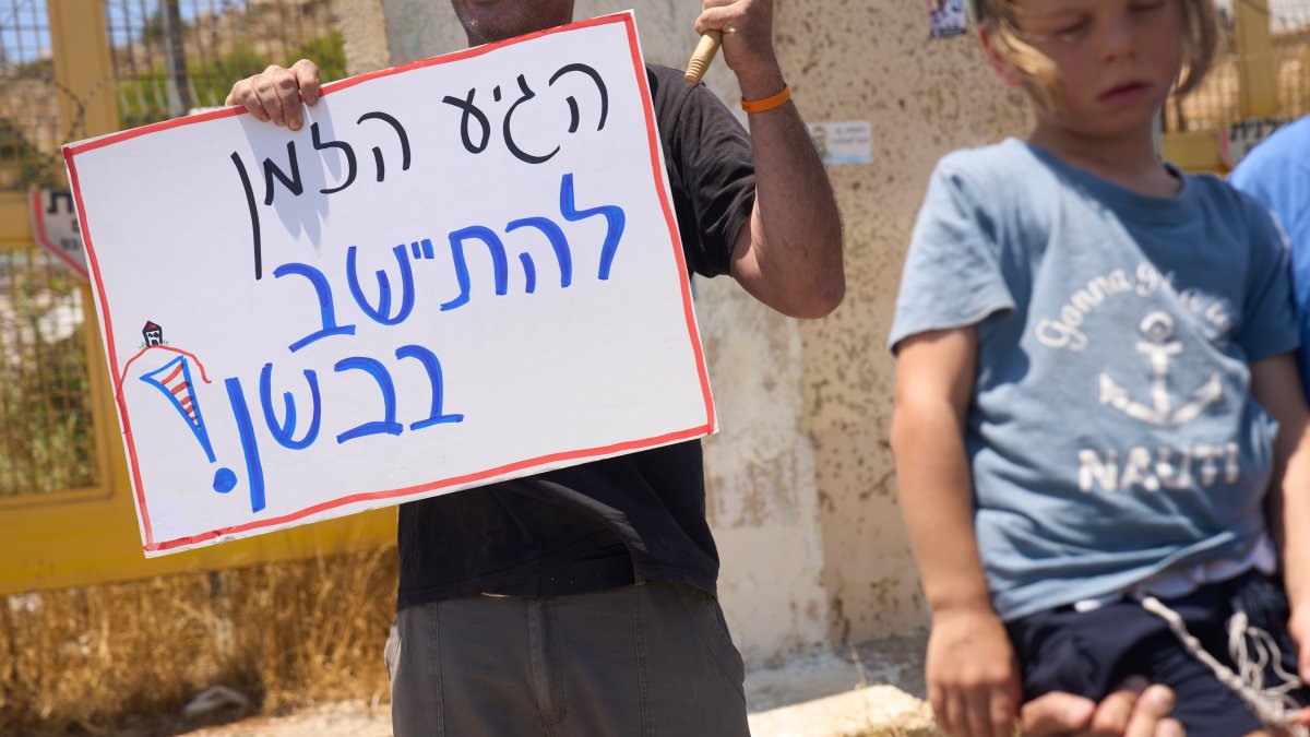 A Jewish extremist holds a sign that reads "It's about time to settle in the Bashan," in the Israeli-occupied Golan Heights, July 21, 2026. (AP Photo)