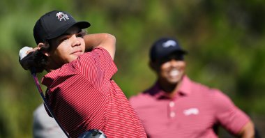 FILE- Charlie Woods tees off on the fifth hole as his father Tiger Woods watches during the final round of the PNC Championship golf tournament, Orlando, U.S., Dec. 22, 2024. (AP Photo)