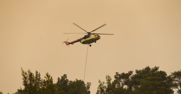 A helicopter drops water over a wildfire as firefighters battle the blaze, Seydikemer, Muğla, southwestern Türkiye, July 29, 2026. (AA Photo)