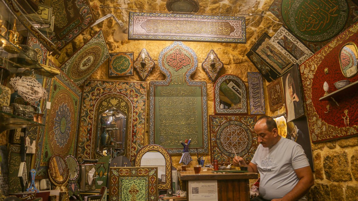 Syrian artisan Eyman Said works inside his workshop displaying traditional wood relief artworks in the historic souks of Aleppo, Syria, July 28, 2026. (AA Photo)