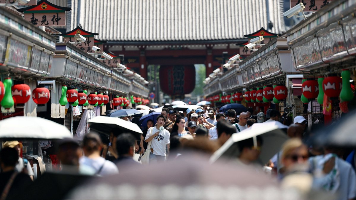 Visitors holding parasols walk along Nakamise Street at the Asakusa district, a popular sightseeing spot, as the Japanese government issued a heatstroke alert in Tokyo and other prefectures due to a heat wave, Tokyo, Japan, July 22, 2026. (Reuters Photo)