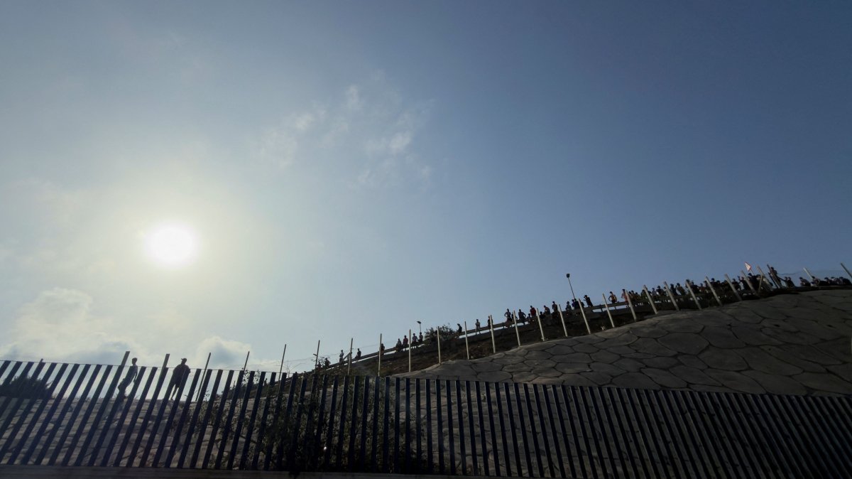 People gather near the border fence between the Spanish enclave of Ceuta and Morocco, hours after thousands of migrants crossed into Ceuta by sea, as seen from Ceuta, Spain, July 30, 2026. (Reuters Photo)