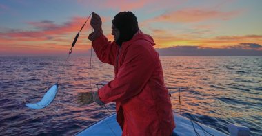 Fisherman Photis Gaitanos catches a toadfish while fishing from his boat off the coast of Larnaca, the island of Cyprus, Dec. 20, 2025. (AP Photo)
