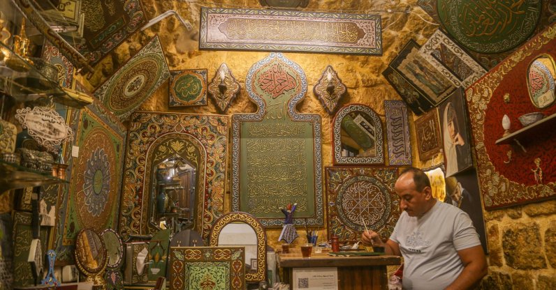 Syrian artisan Eyman Said works inside his workshop displaying traditional wood relief artworks in the historic souks of Aleppo, Syria, July 28, 2026. (AA Photo)