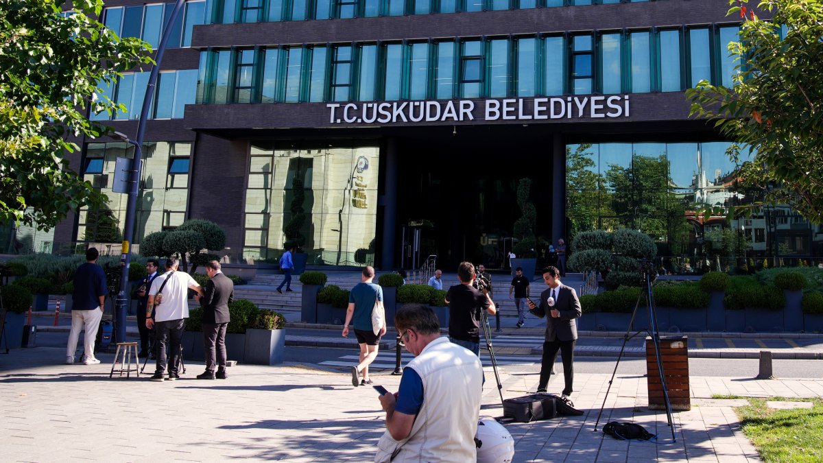 A journalist livestreams outside the Üsküdar Municipality building as people pass by following corruption allegations involving the district's mayor in Üsküdar, Istanbul, Türkiye, July 29, 2026. (AA Photo)
