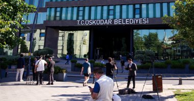 A journalist livestreams outside the Üsküdar Municipality building as people pass by following corruption allegations involving the district's mayor in Üsküdar, Istanbul, Türkiye, July 29, 2026. (AA Photo)