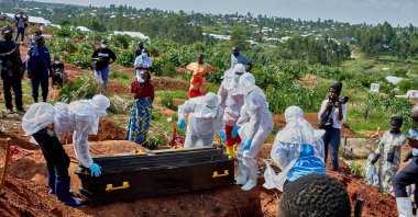 Red Cross workers wearing personal protective equipment (PPE) prepare to lower the coffin of an Ebola virus victim, at the Nyamurongo cemetery, Bunia, DRC, May 26, 2026. (Reuters Photo)