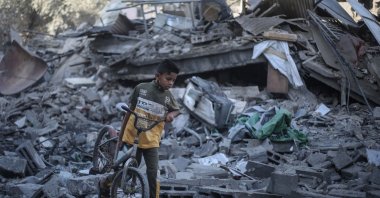 A Palestinian boy walks his bicycle through the rubble of a destroyed building after it was targeted by Israeli strikes the previous night, in Deir al-Balah, central Gaza Strip, July 29, 2026. (AFP Photo)