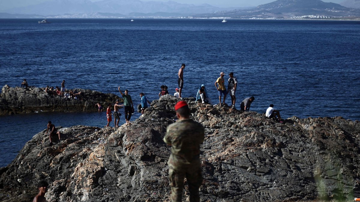 A member of the Spanish army watches a group of migrants near the border post of the Spanish enclave of Ceuta, Aug. 2, 2026. (AFP Photo)