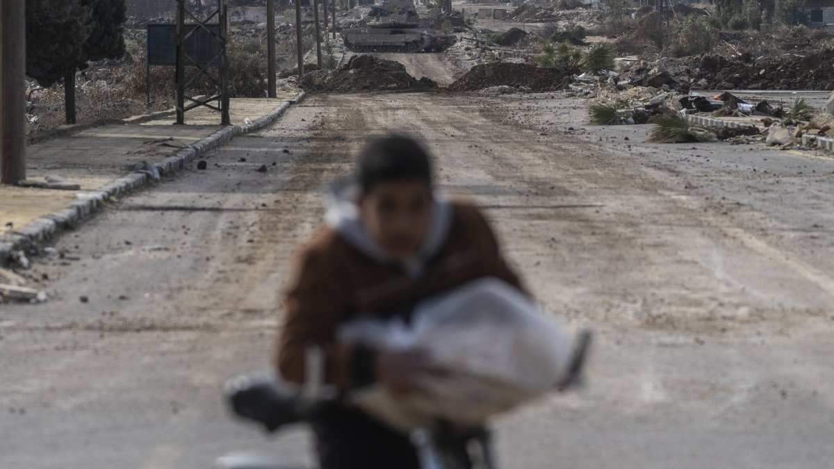 This file photo shows a boy cycling home as Israeli military armored vehicles block a road leading to the town of Quneitra, Syria, Jan. 5, 2025. (AP Photo)