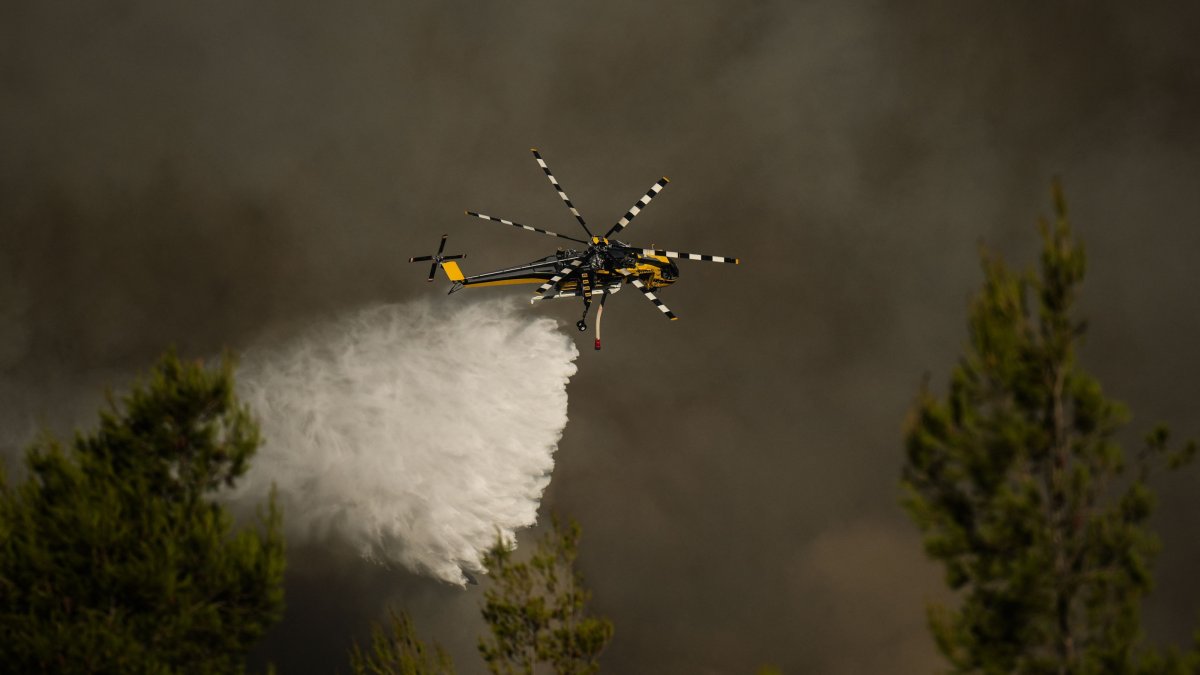 A firefighting helicopter drops water over a cloud of smoke of a wildfire in the area of Porto Germeno, near Athens, Greece, Aug. 2, 2026. (AFP Photo)