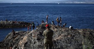 A member of the Spanish army watches a group of migrants near the border post of the Spanish enclave of Ceuta, Aug. 2, 2026. (AFP Photo)