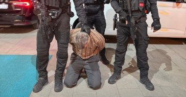 An undated photo of Burkay Karatepe kneeling among police officers after his capture, Afyonkarahisar, Türkiye. (IHA Photo)