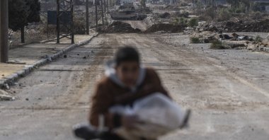This file photo shows a boy cycling home as Israeli military armored vehicles block a road leading to the town of Quneitra, Syria, Jan. 5, 2025. (AP Photo)