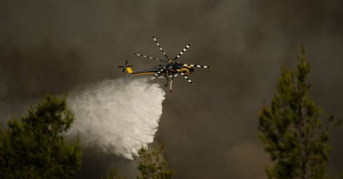 A firefighting helicopter drops water over a cloud of smoke of a wildfire in the area of Porto Germeno, near Athens, Greece, Aug. 2, 2026. (AFP Photo)