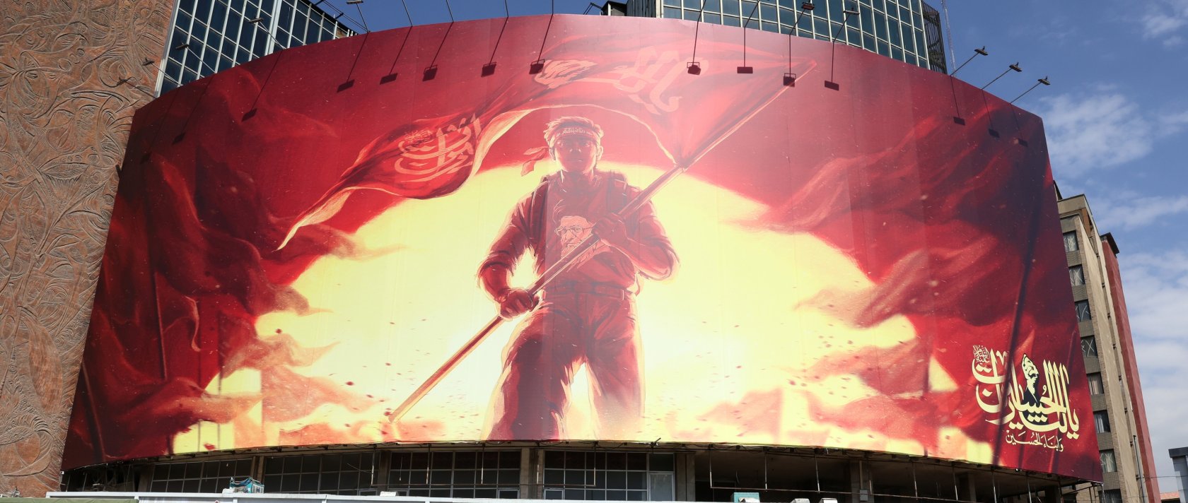 A man holds Iran's national flag in front of a large political billboard at Valiasr Square in Tehran, Iran, Aug. 1, 2026. (EPA Photo)