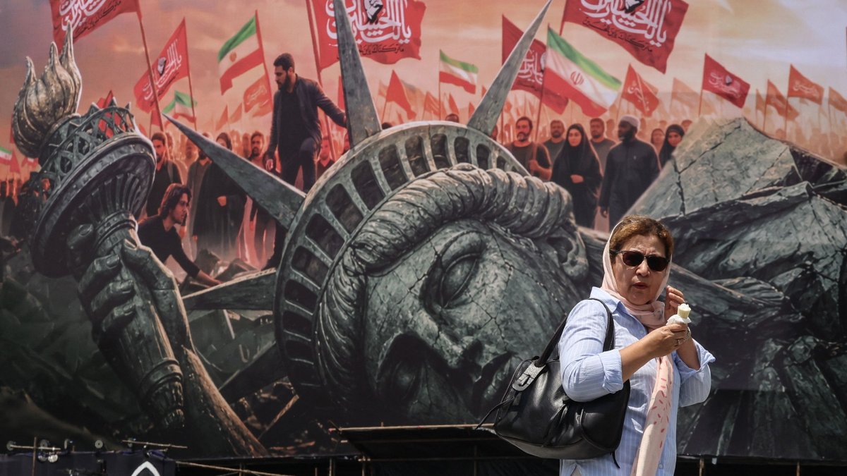 An Iranian woman walks past an anti-U.S. billboard at Enghelab Square in central Tehran, Iran, Aug. 3, 2026. (AFP Photo)