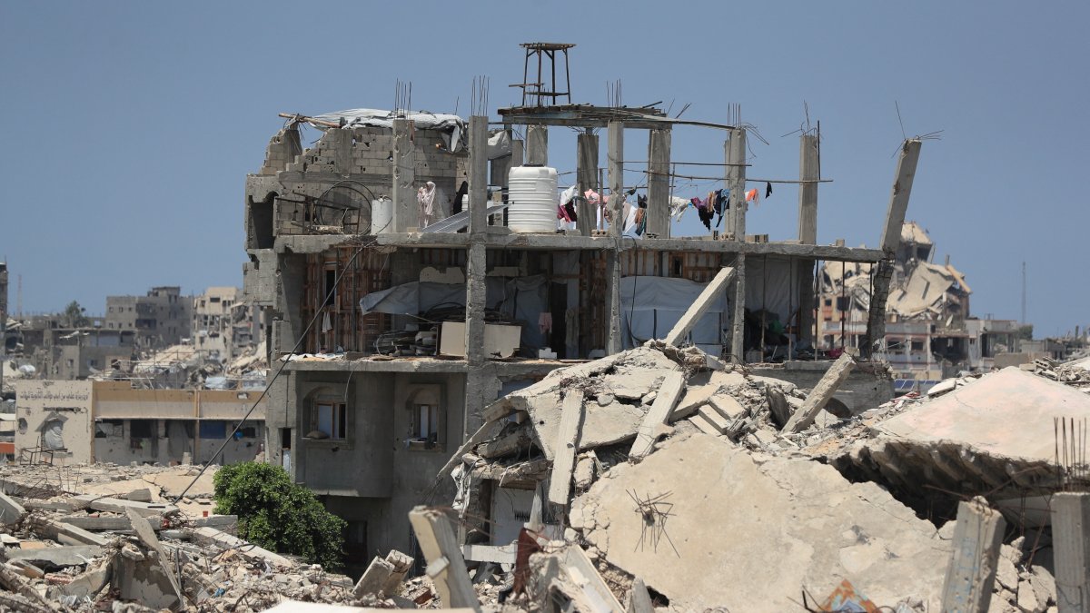 A Palestinian woman stands on the roof of a house damaged during the war, surrounded by destroyed buildings, in Gaza City, Palestine, Aug. 1, 2026. (Reuters Photo)