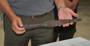 An expert holds an artifact discovered at the historic site of Malazgirt, Muş, Türkiye, July 31, 2026. (AA Photo)
