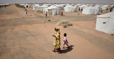 A woman and a child, displaced from North Darfur's capital, el-Fasher or other conflict-affected areas, walk in the newly established el-Afadh camp in al Dabbah, Northern State, Sudan, Nov. 13, 2025. (AP Photo)
