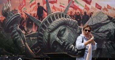 An Iranian woman walks past an anti-U.S. billboard at Enghelab Square in central Tehran, Iran, Aug. 3, 2026. (AFP Photo)
