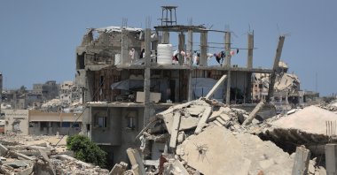 A Palestinian woman stands on the roof of a house damaged during the war, surrounded by destroyed buildings, in Gaza City, Palestine, Aug. 1, 2026. (Reuters Photo)