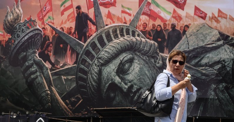 An Iranian woman walks past an anti-U.S. billboard at Enghelab Square in central Tehran, Iran, Aug. 3, 2026. (AFP Photo)