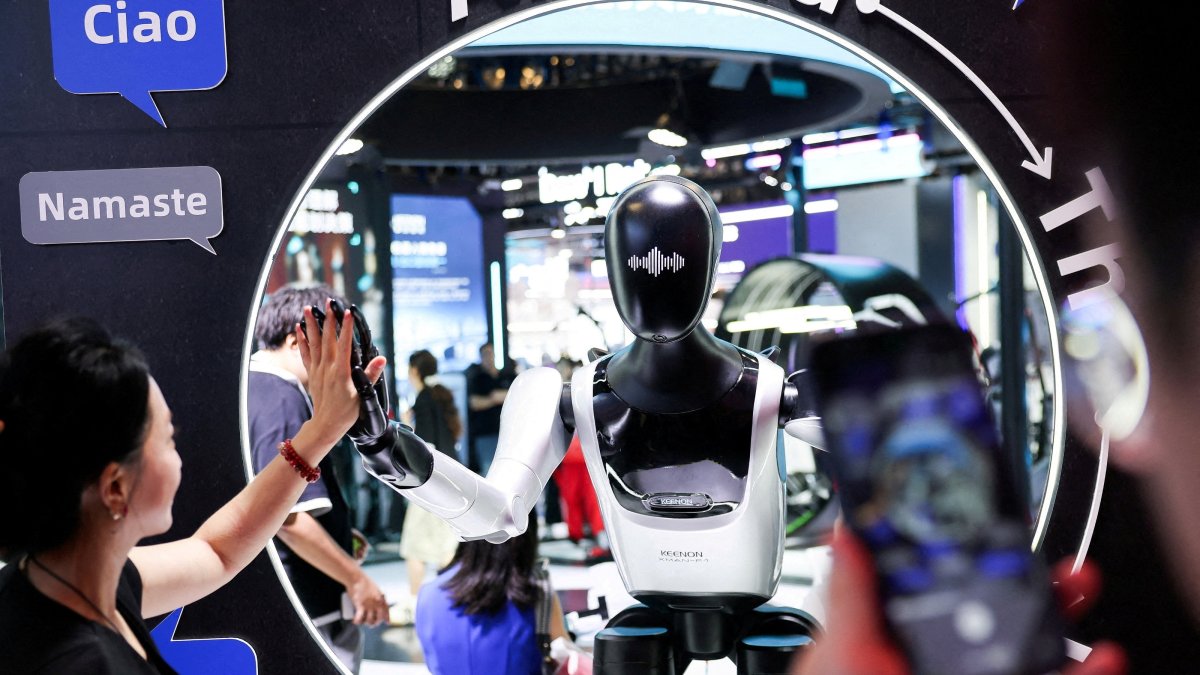 A visitor high-fives a humanoid robot at the Keenon Robotics booth during the World Artificial Intelligence Conference (WAIC), Shanghai, China, July 18, 2026. (Reuters Photo)