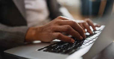 A close-up view of a woman working on a laptop. (Shutterstock Photo)