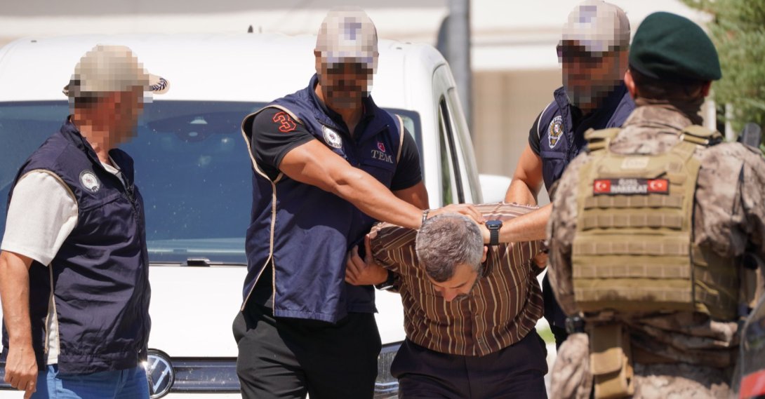 Police officers escort Burkay Karatepe as he is brought to a courthouse, Muğla, southwestern Türkiye, Aug. 5, 2026. (AA Photo)