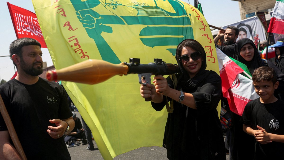A woman holds a mock-up of a rocket-propelled grenade (RPG) next to a Hezbollah flag during the Arbaeen rally in Tehran, Iran, Aug. 4, 2026. (Reuters Photo)