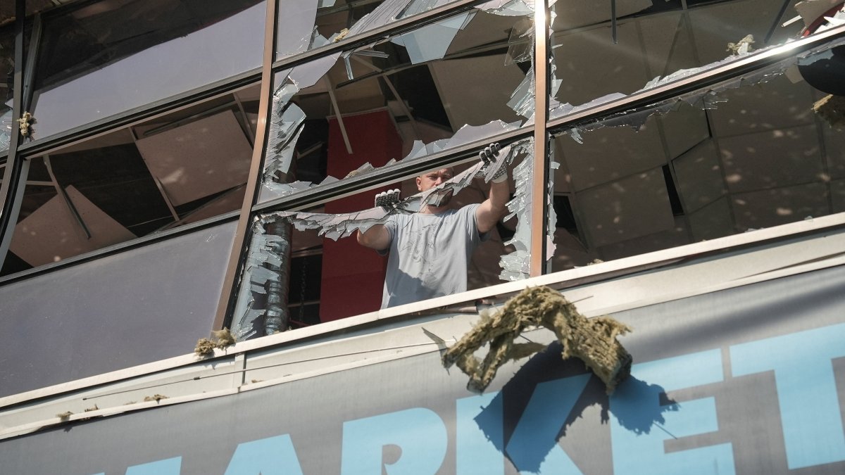 A resident removes pieces of glass from broken windows in a shopping mall hit by a Russian airstrike in Sumy, Ukraine, Aug. 6, 2026. (Reuters Photo)