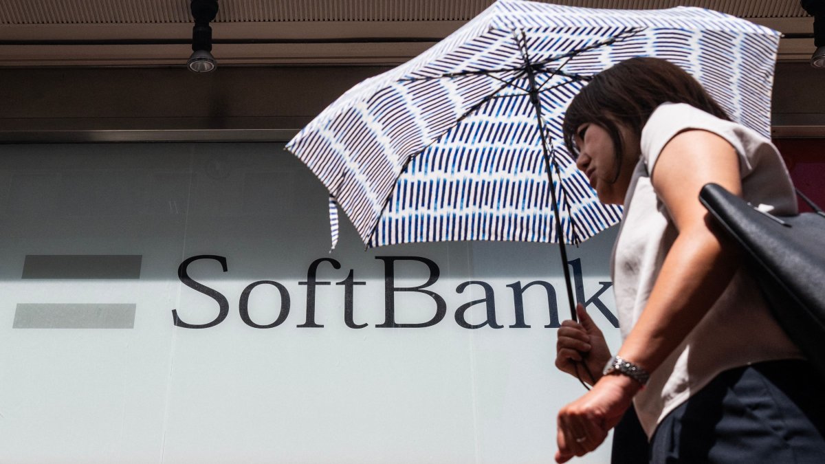 A commuter walks past a Softbank logo on the side of a building, Tokyo, Japan, Aug. 6, 2026. (AFP Photo)