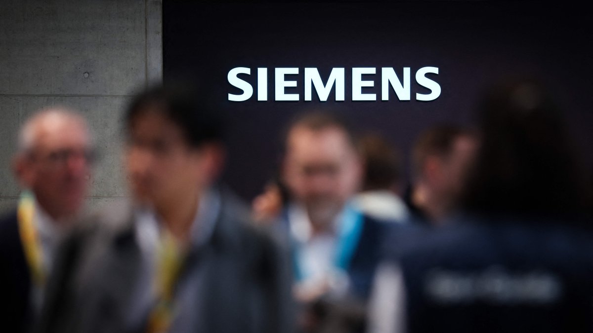 Visitors are seen at the booth of German industrial conglomerate Siemens with an illuminated logo during the Hannover industrial trade fair, Hannover, Germany, April 20, 2026. (AFP Photo)