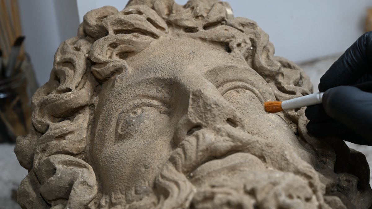 An expert works on a statue head unearthed during excavations at the ancient city of Aspendos, Antalya, southern Türkiye, Aug. 5, 2026. (AA Photo)