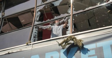 A resident removes pieces of glass from broken windows in a shopping mall hit by a Russian airstrike in Sumy, Ukraine, Aug. 6, 2026. (Reuters Photo)