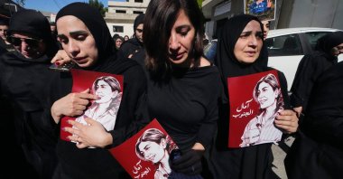 Mourners hold posters that show portraits of Lebanese journalist Amal Khalil, who was killed in an Israeli airstrike, during her funeral procession in the village of Baysariyeh, southern Lebanon, April 23, 2026. (AP Photo)