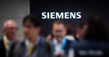 Visitors are seen at the booth of German industrial conglomerate Siemens with an illuminated logo during the Hannover industrial trade fair, Hannover, Germany, April 20, 2026. (AFP Photo)