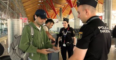 Spanish national police officers check the documents of travellers arriving from Italy, after Spain's government said it would establish border controls for flights and ships from Italy, at Madrid-Barajas Airport, Madrid, Spain, Aug. 8, 2026. (Reuters Photo)