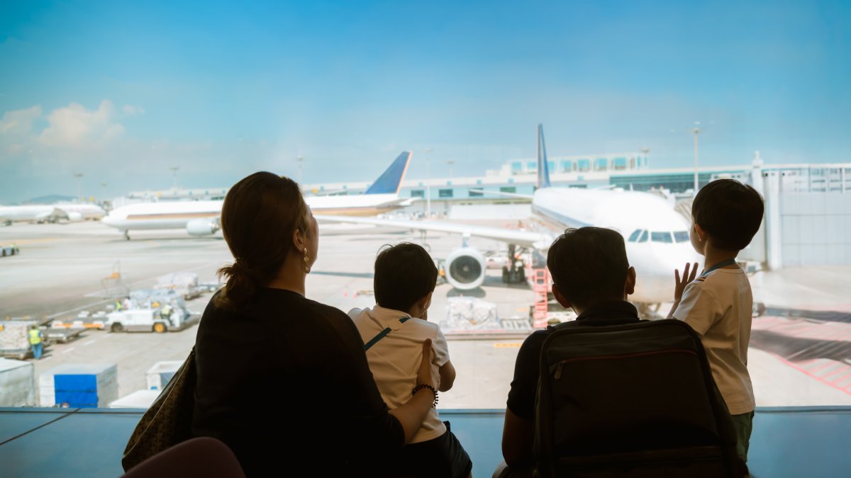 A family with kids looks at airplanes in a terminal while waiting for their flight, Changi Airport, Singapore. (Shutterstock Photo)