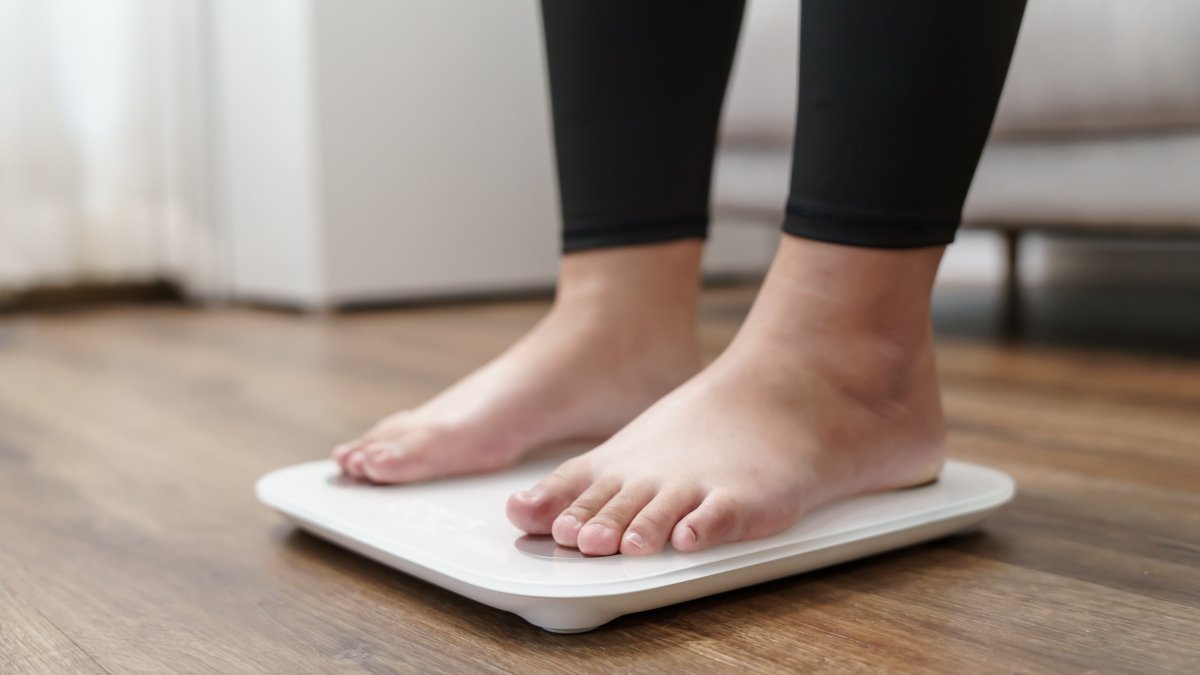 A person stands on an electronic scale during a weight measurement. (Shutetrstock Photo)
